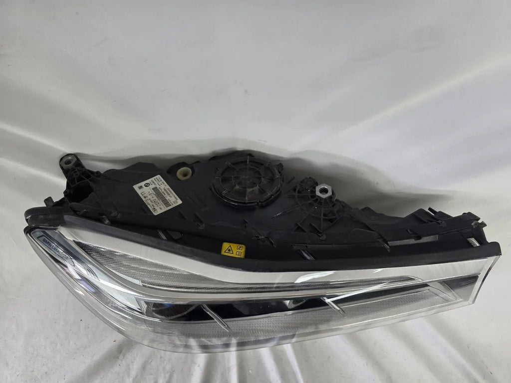 Used genuine BMW Laser headlight for 7 Series models G11 and G12. This right-side OEM headlamp, part number 7465606, features advanced laser lighting technology for superior visibility and performance. The image shows the original BMW right laser headlight in used condition, highlighting the detailed lens design, housing structure, and connector ports — ideal for high-end replacement or repair on compatible 7 Series vehicles.