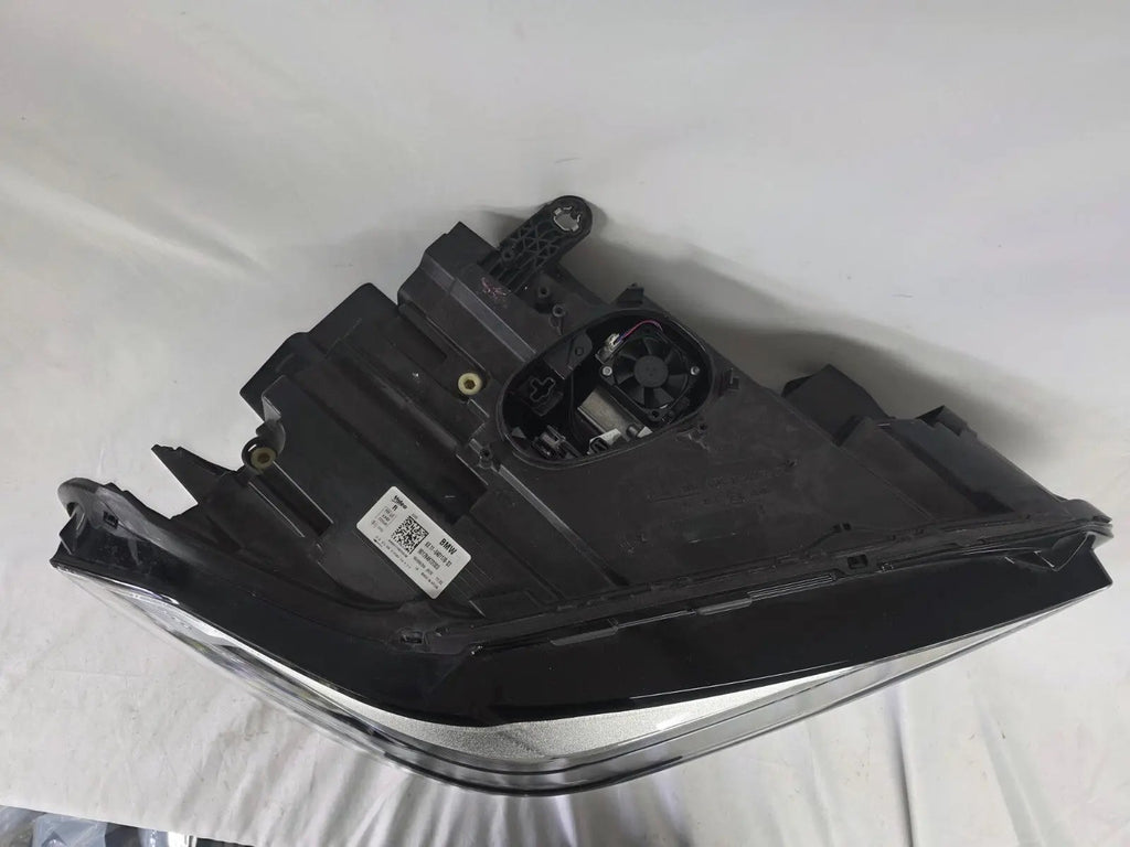 Used genuine BMW Adaptive LED headlight for X1 F48 LCI (facelift) model. This right-side OEM headlamp, part number 5A01178, is equipped with adaptive lighting technology for improved night visibility and cornering performance. The image displays the original right Adaptive LED headlight in used condition, showing the clear lens, mounting brackets, and electrical connectors — an ideal OEM replacement for BMW X1 F48 LCI vehicles.

