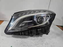 Load image into Gallery viewer, Genuine used Mercedes-Benz Bi-Xenon headlight for GLA-Class model X156. This left-side (LH) OEM headlamp, part number A1569061700, features Bi-Xenon lighting technology for enhanced night visibility and a focused beam pattern. The image shows the original left headlight in used condition, highlighting the lens clarity, projector unit, mounting brackets, and electrical connector — ideal for replacing a damaged headlamp on compatible Mercedes-Benz GLA X156 vehicles.

