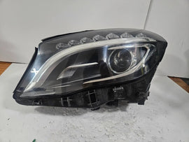 Genuine used Mercedes-Benz Bi-Xenon headlight for GLA-Class model X156. This left-side (LH) OEM headlamp, part number A1569061700, features Bi-Xenon lighting technology for enhanced night visibility and a focused beam pattern. The image shows the original left headlight in used condition, highlighting the lens clarity, projector unit, mounting brackets, and electrical connector — ideal for replacing a damaged headlamp on compatible Mercedes-Benz GLA X156 vehicles.

