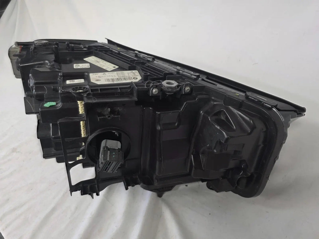 Genuine OEM BMW Laser headlight for 5 Series models G30, G31, and F90 LCI (facelift). This left-side headlamp, part number 5A388D5, is equipped with advanced laser lighting technology for superior visibility and precision on the road. The image displays the original left laser headlight in used condition, clearly showing the lens structure, cooling fins, mounting points, and connector ports — ideal for OEM replacement on compatible BMW 5 Series LCI vehicles.

