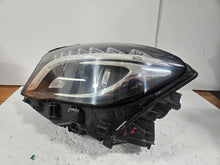 Load image into Gallery viewer, Genuine used Mercedes-Benz Bi-Xenon headlight for GLA-Class model X156. This left-side (LH) OEM headlamp, part number A1569061700, features Bi-Xenon lighting technology for enhanced night visibility and a focused beam pattern. The image shows the original left headlight in used condition, highlighting the lens clarity, projector unit, mounting brackets, and electrical connector — ideal for replacing a damaged headlamp on compatible Mercedes-Benz GLA X156 vehicles.
